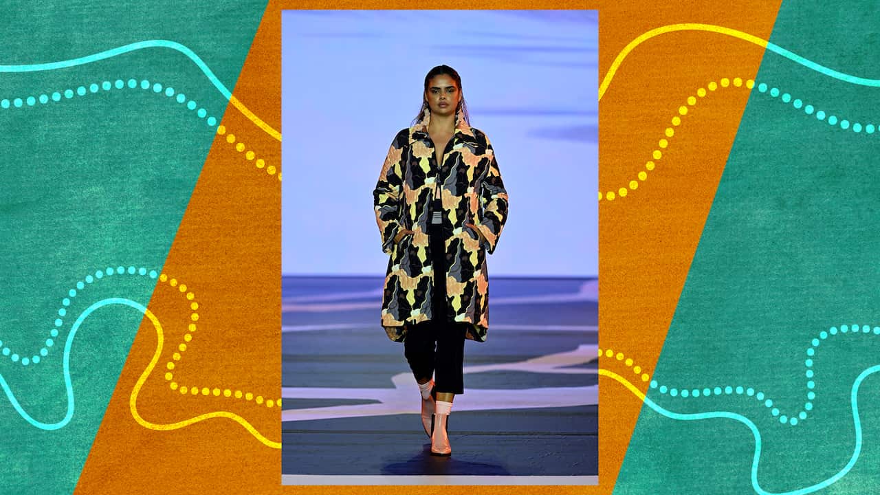 A model walks the runway in a multi-coloured, splash design coat and pink boots 