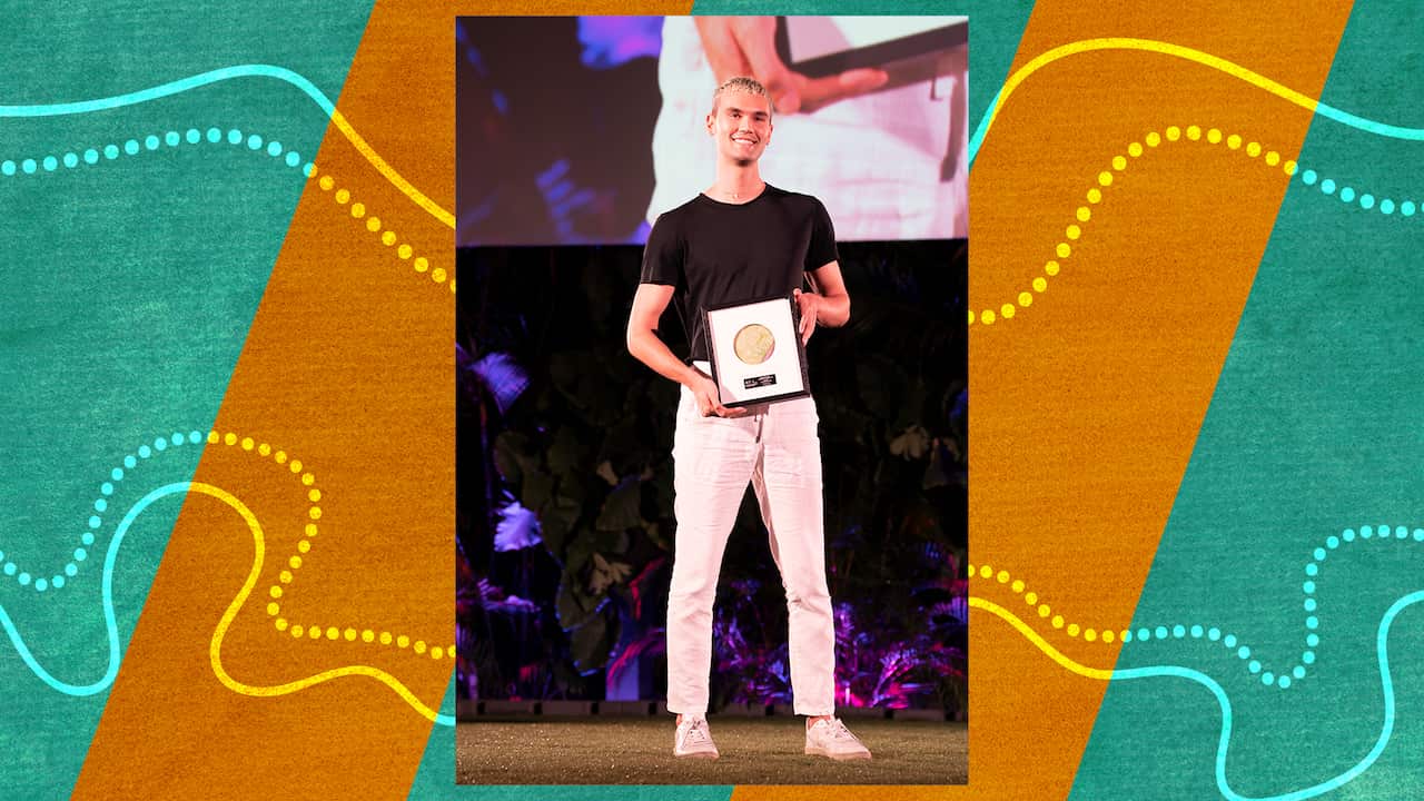 A young man holds an award on stage