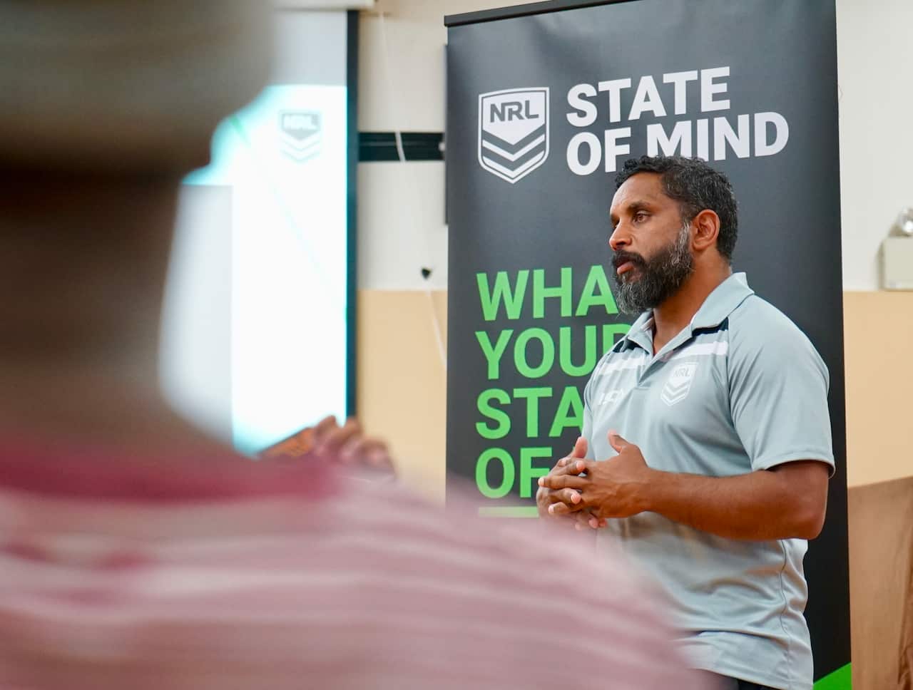 Preston Campbell speaking in front of the NRL's State of Mind corflute