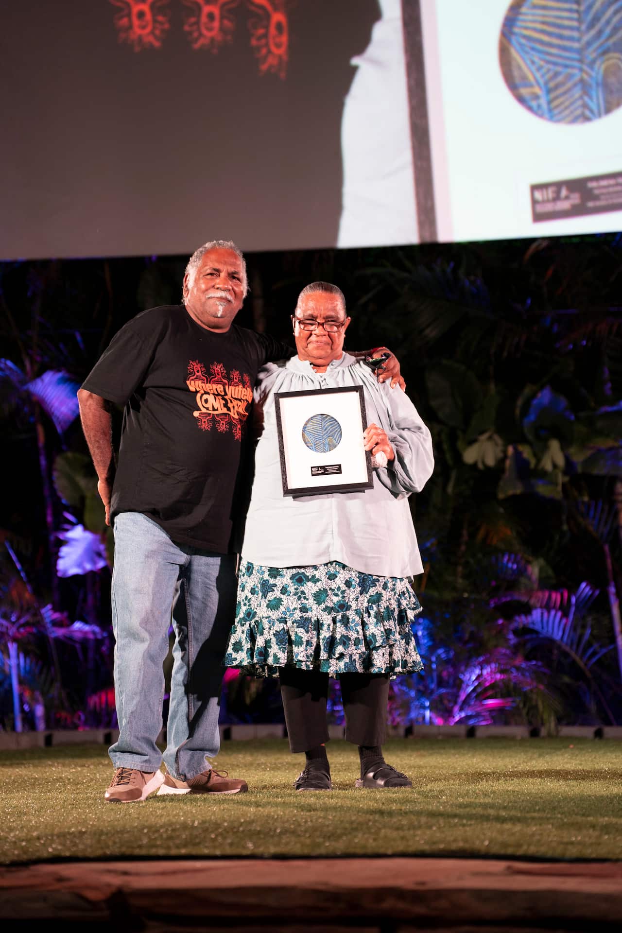 A man and woman accept an award and smile