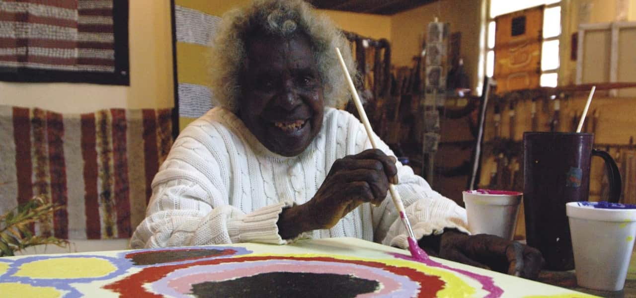 A woman who is painting smiles for a photo
