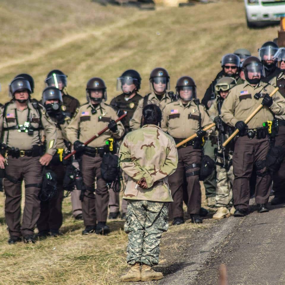 A peaceful protestor stands in defiance of a line of riot police at Standing Rock in North Dakota, USA
