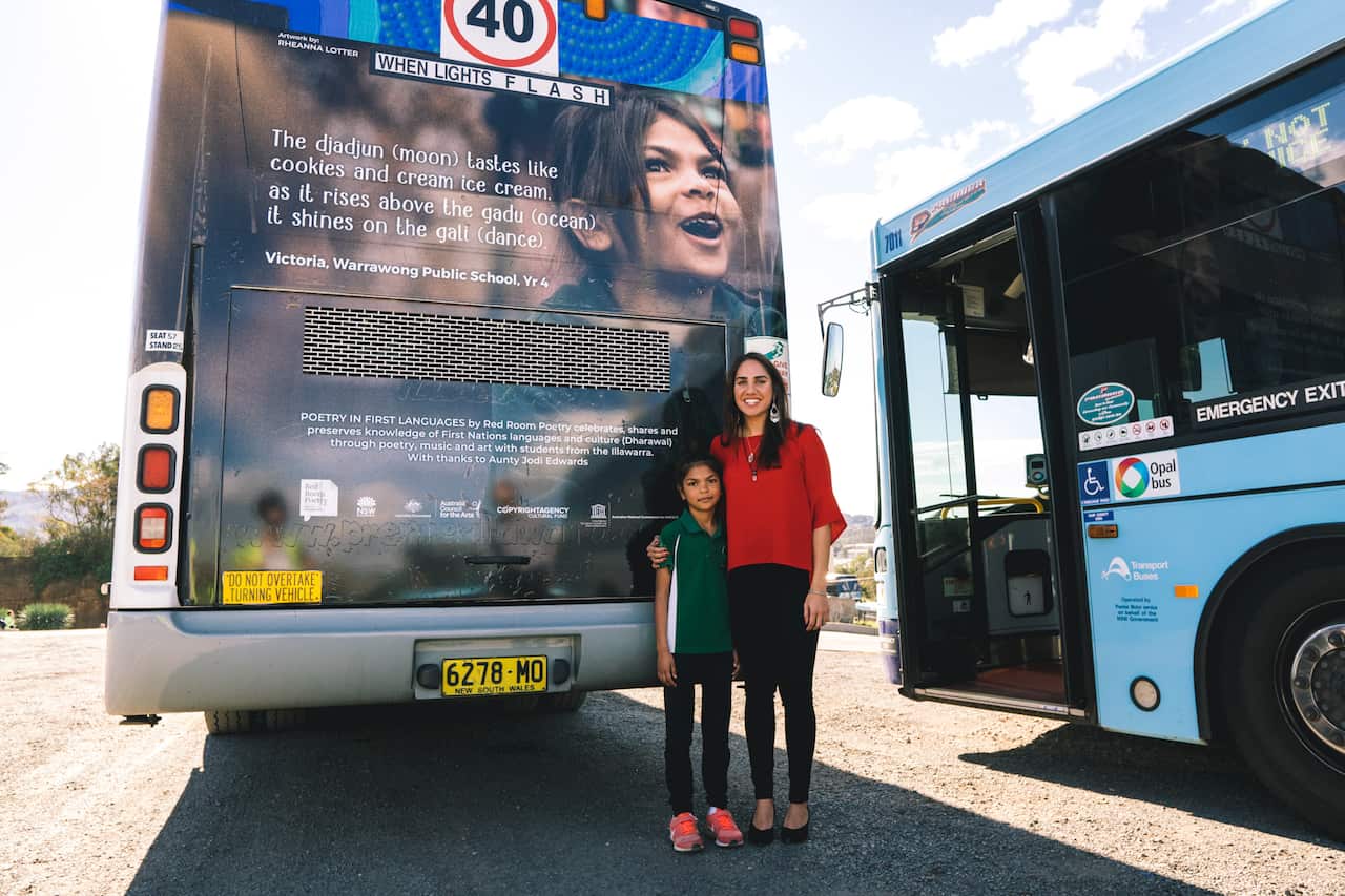 Kirli Saunders and young poet Victoria with her poem on the back of a bus
