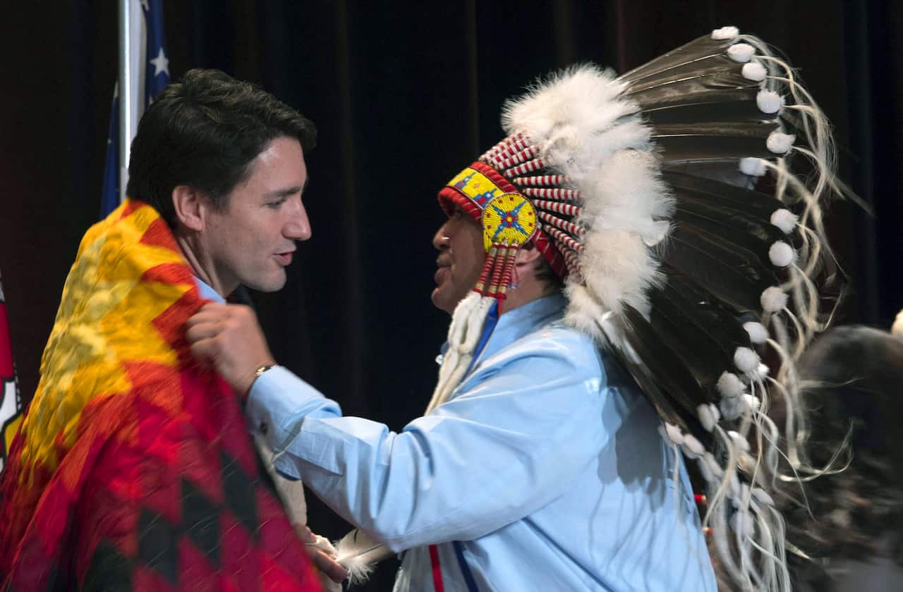 AFN National Chief Perry Bellegarde adjusts a blanket presented to Canada's Prime Minister Justin Trudeau following speeches at the Assembly of First Nations Special Chiefs Assembly in Gatineau, Quebec.