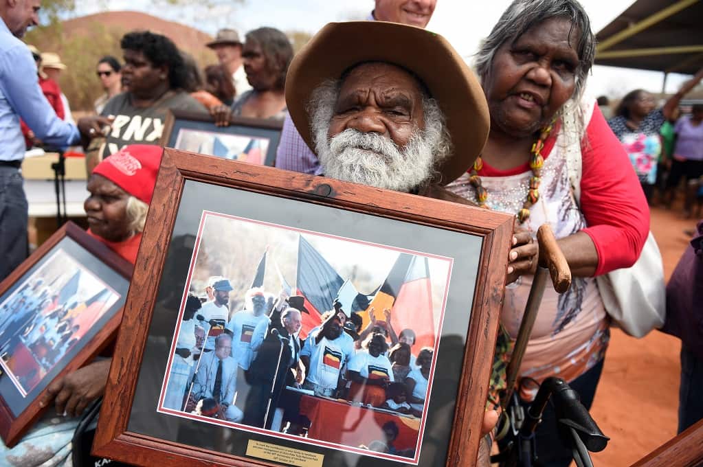 Reggie Uluru holds a frames photograph of himself at the original handback in 1985, during an event to mark the 30th anniversary of the event at the community of Mutitjulu in the Northern Territory, Monday, Oct. 26, 2015. (AAP Image/Dan Peled) 