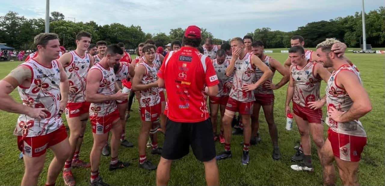 The waratah afl nt team stand around their coach. 