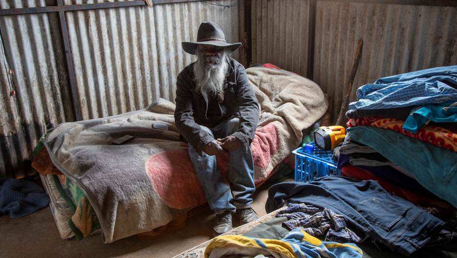a man sits on a bed in a tin house 