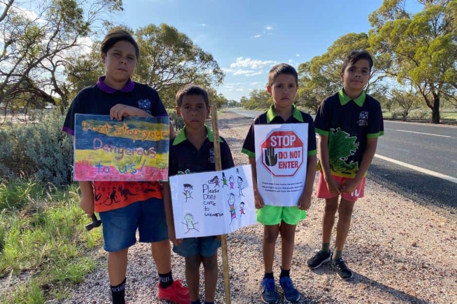 Kids with more home-made iugns standing by highway