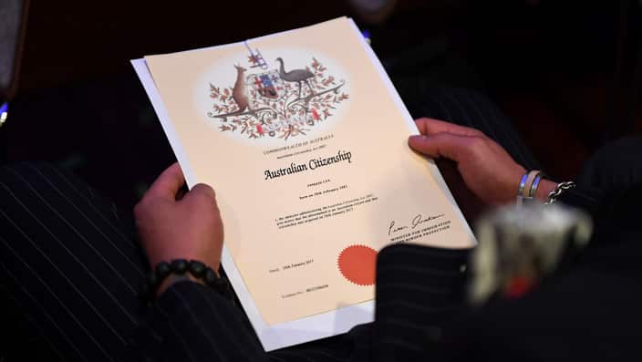 An Australian citizenship recipient holds his certificate during a citizenship ceremony on Australia Day.