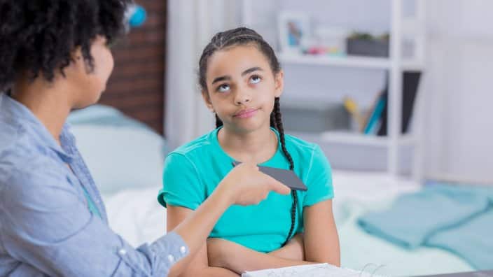 Preteen girl rolls eyes as mom takes away her phone