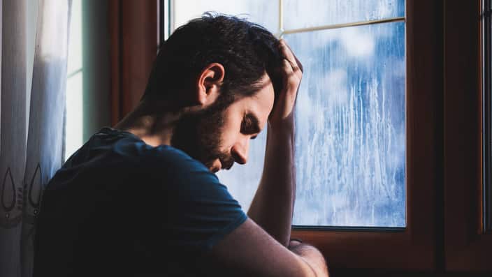 Young sad mad sitting by a window