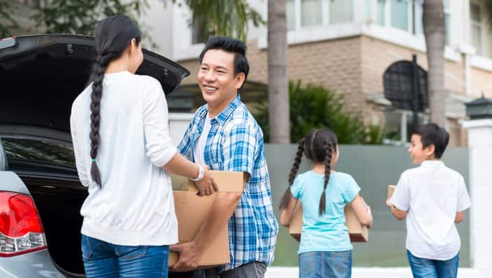 Parents and children unloading boxes from car to the new house