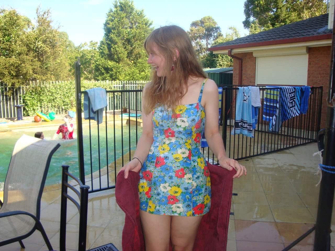 Young woman looking to side at the pool, laughing.