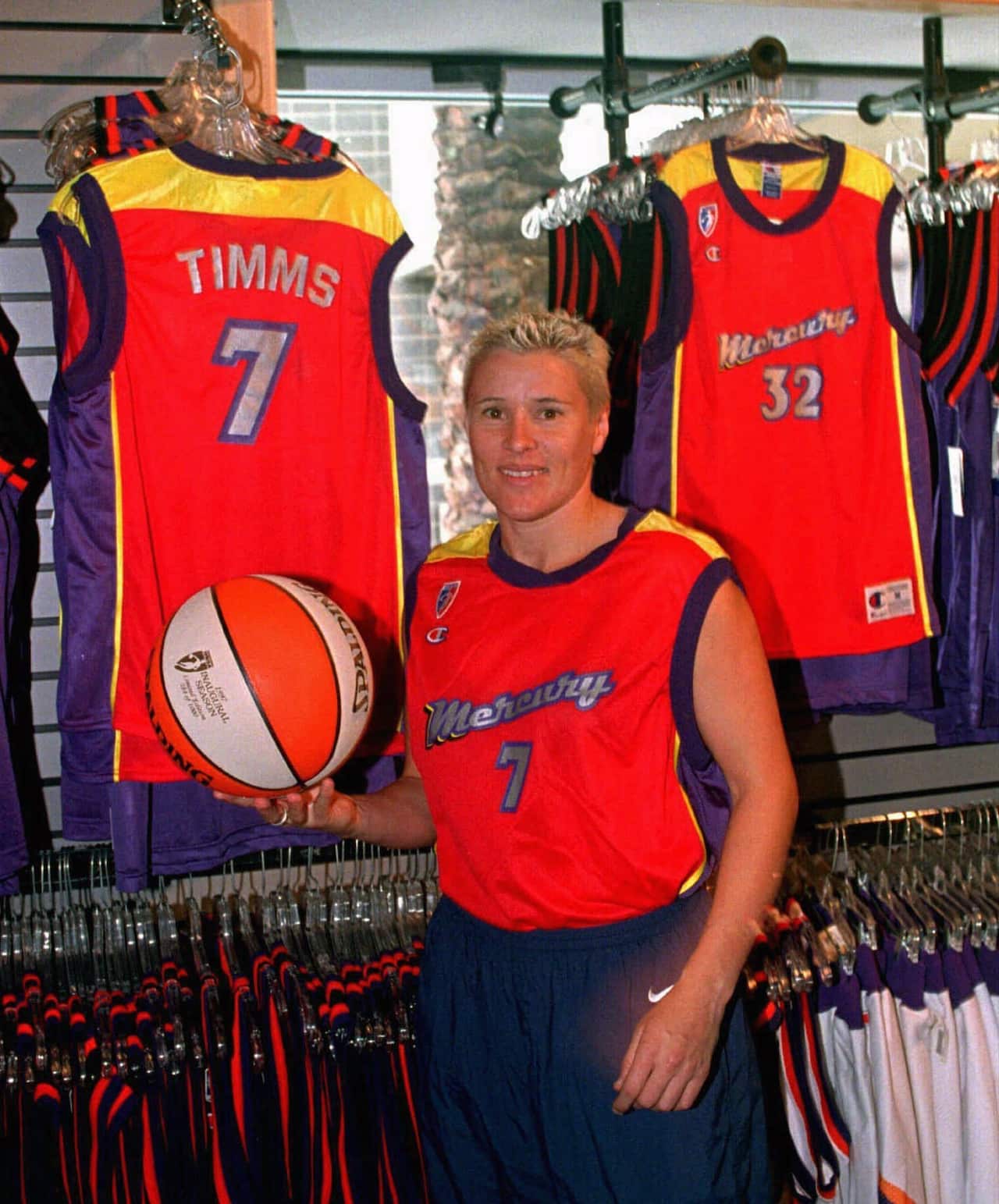 Michele Timms, of the WNBA Phoenix Mercury holds a WNBA basketball as she stands beside Mercury merchandise at the team store in the America West Arena, Wednesday Feb. 18, 1998.