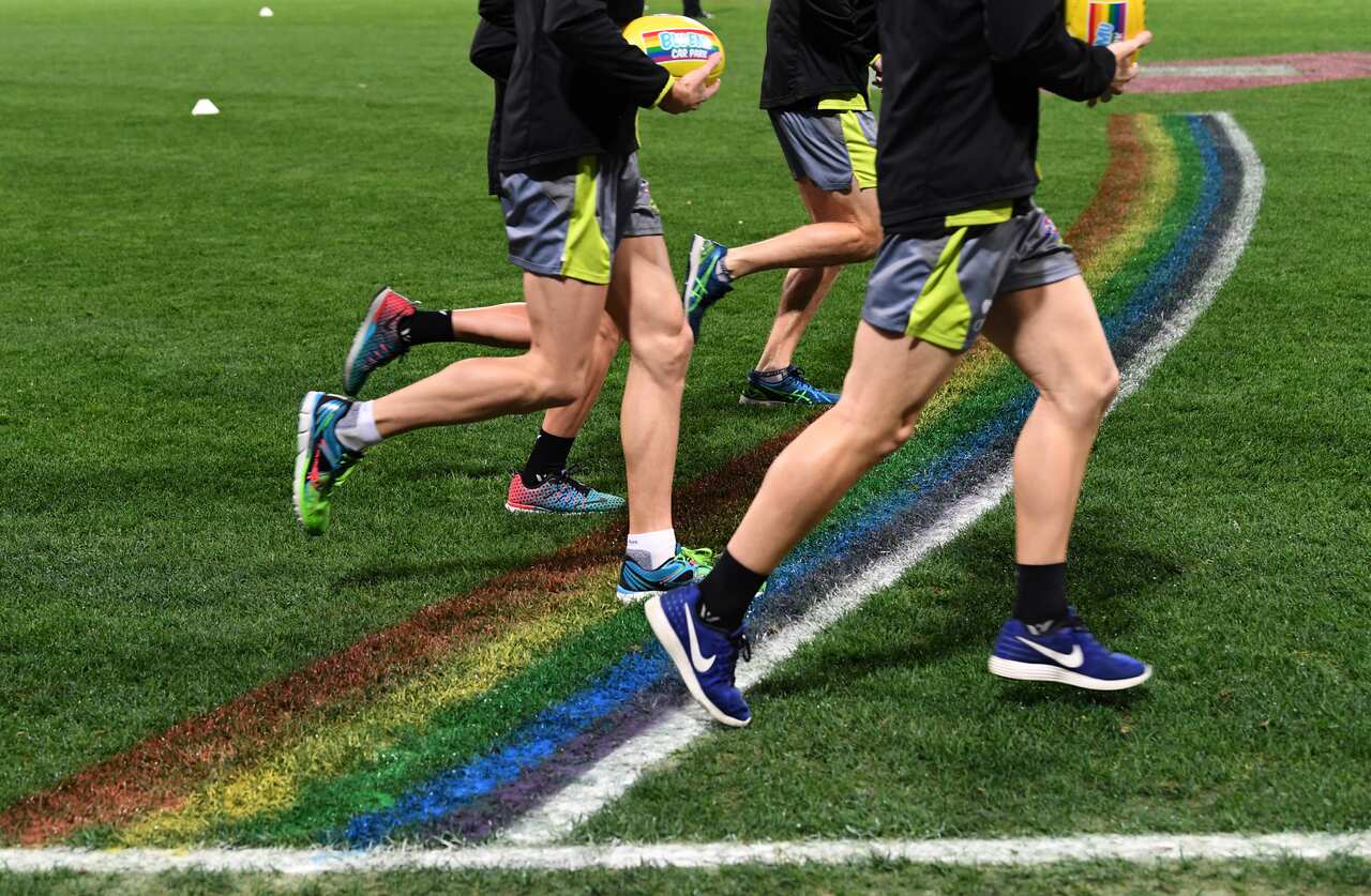 Match officials run past the rainbow colours painted on the the 50 metre line before the AFL Round 18 'Pride Game', 2017.