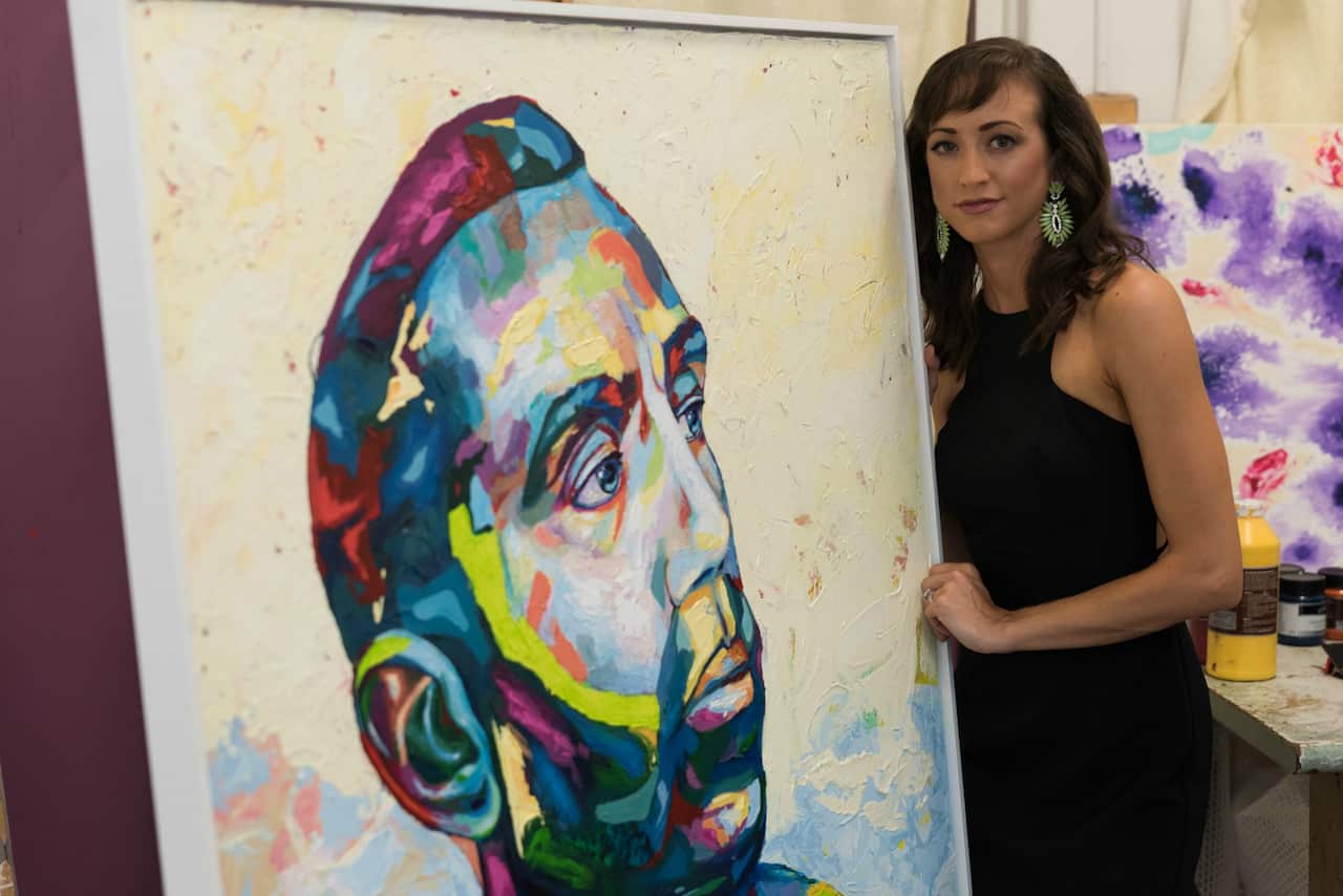 Artist Megan Adams with her portrait of Adam Goodes