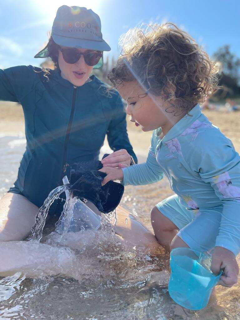 Woman and child at beach playing with buckets of water.