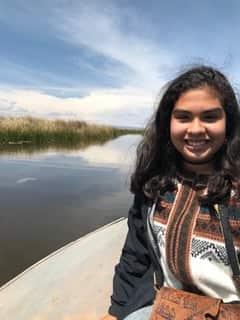Young woman of Peruvian descent on a boat in a river, smiling at camera.