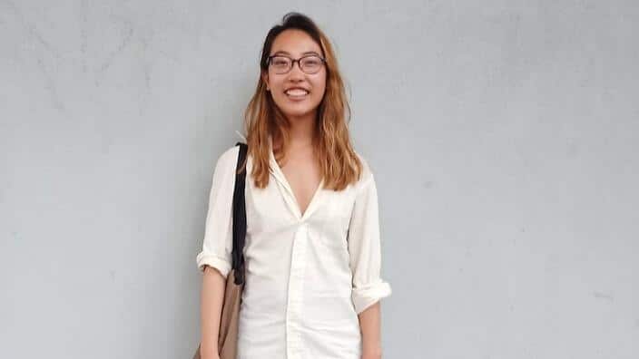 Cat Yen standing in front of a grey wall, smiling at the camera. 