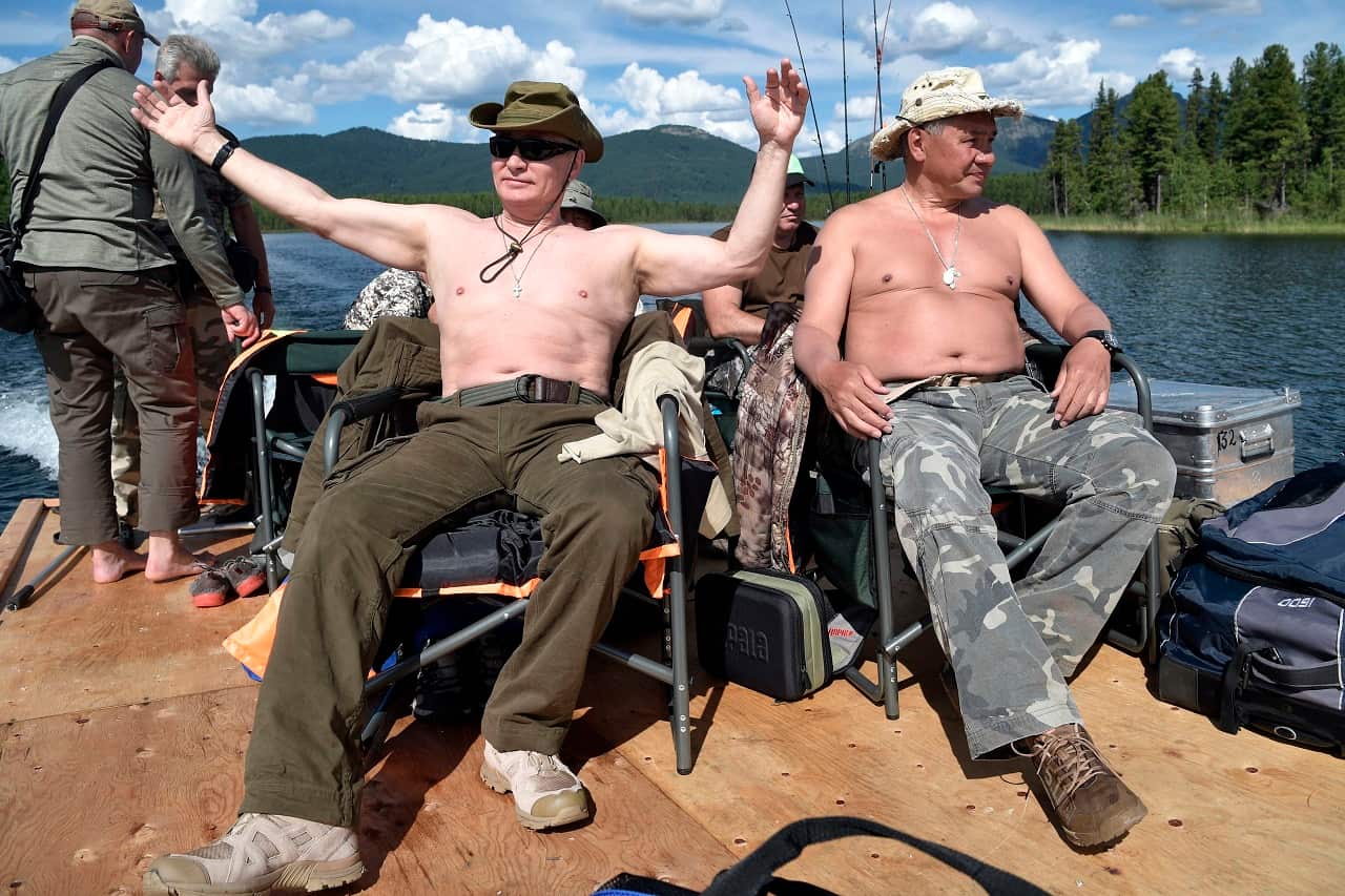 Russian President Vladimir Putin, left, and Defense Minister Sergei Shoigu rest after fishing during a mini-break in the Siberian Tyva region.
