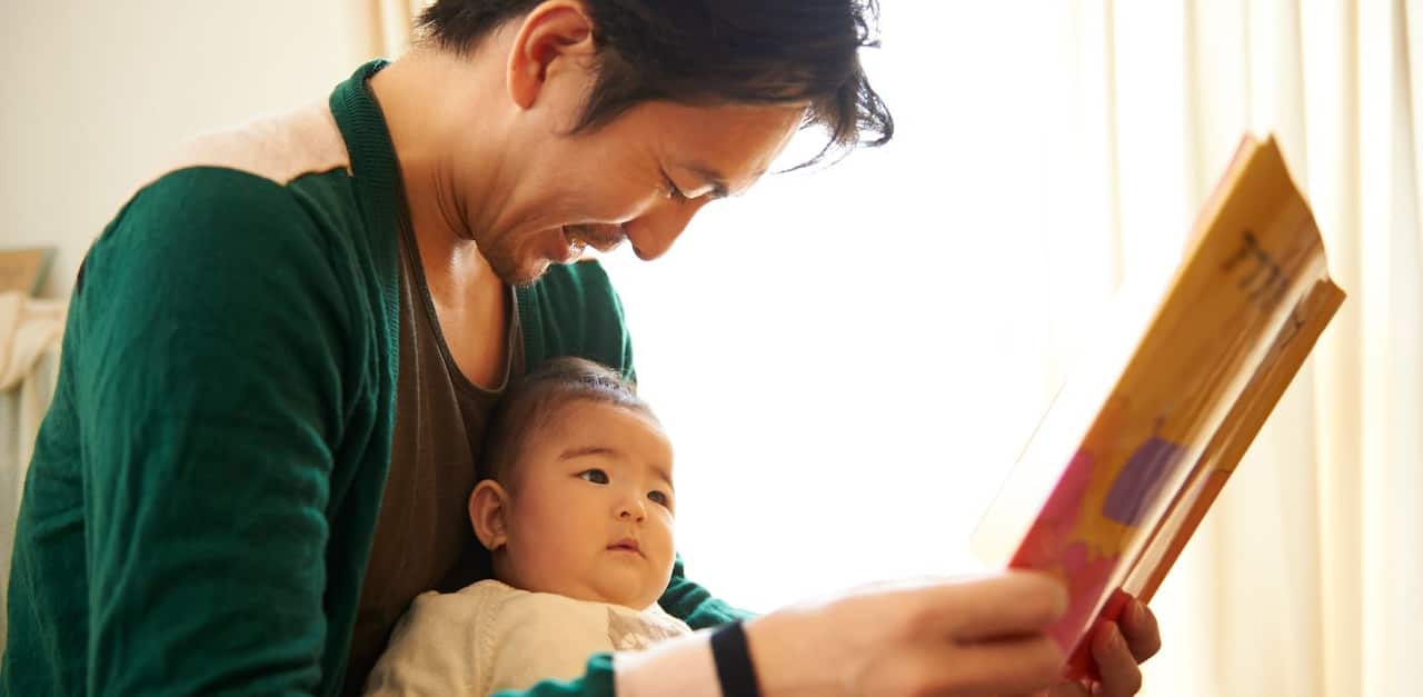 a father reads to his baby child
