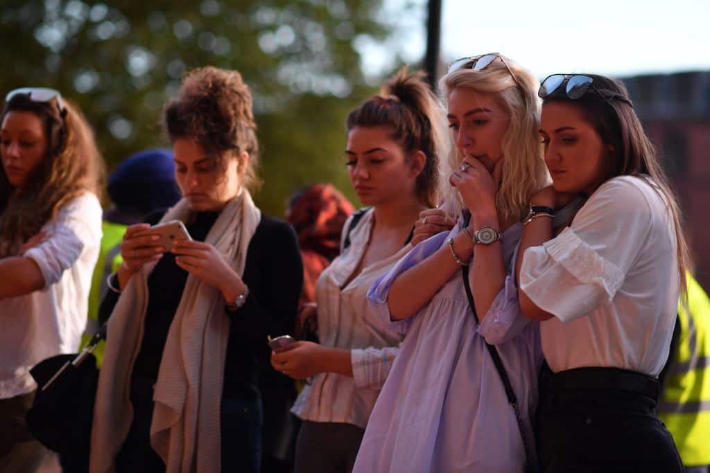 People pause in front of floral tributes in Albert Square in Manchester, in solidarity with those killed and injured in attack at the Ariana Grande concert.
