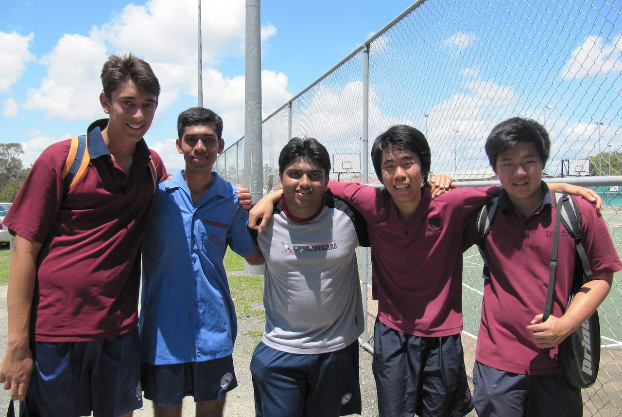 A group of five teen boys posing in school sports uniform, arms around each other's shoulders. 