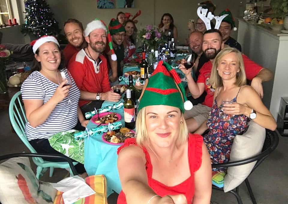 Large group of people sitting around a long table, smiling at camera.