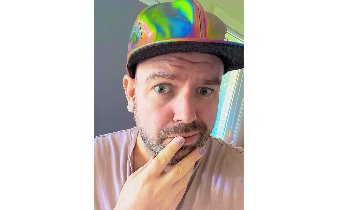 Gender diverse person with nail polish and rainbow cap