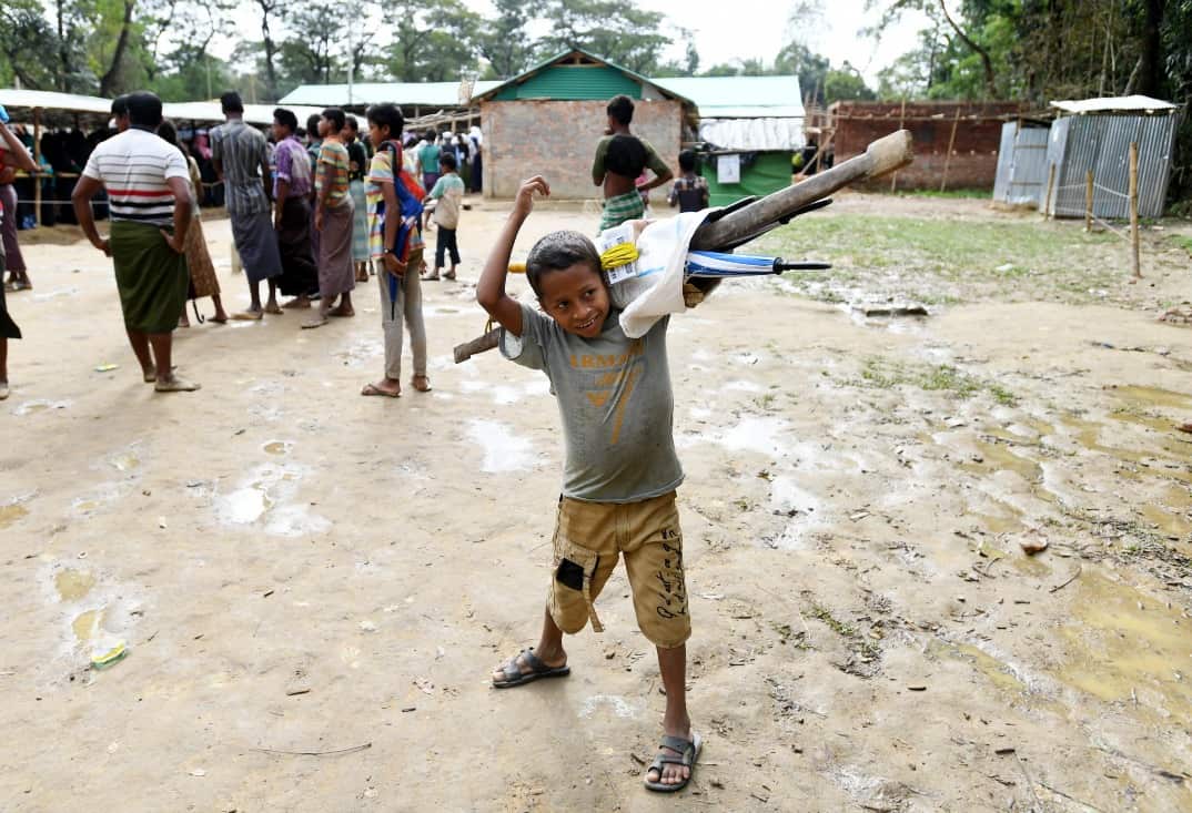 A child carries umbrellas on his shoulders at the Balukhali food distribution centre near Cox's Bazar in Bangladesh on Monday, December 11, 2017. 
