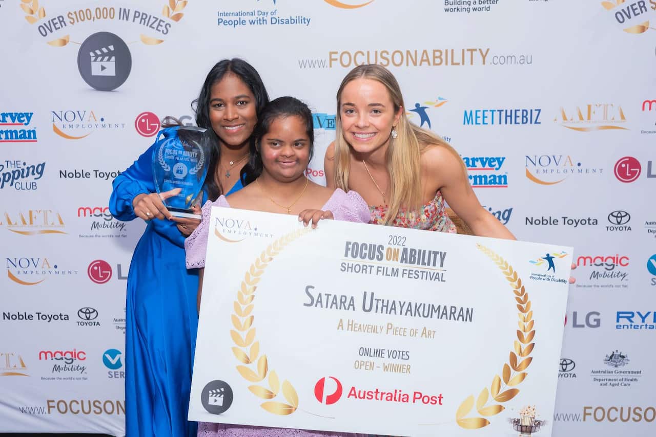 Three young women accepting a trophy and giant prize check.