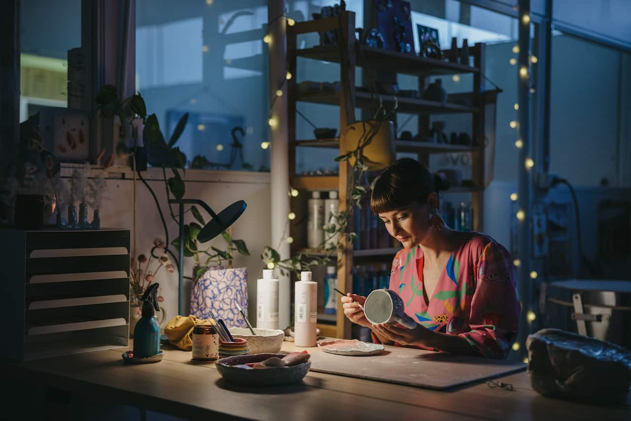 Nirrimi sits in her studio, painting ceramics