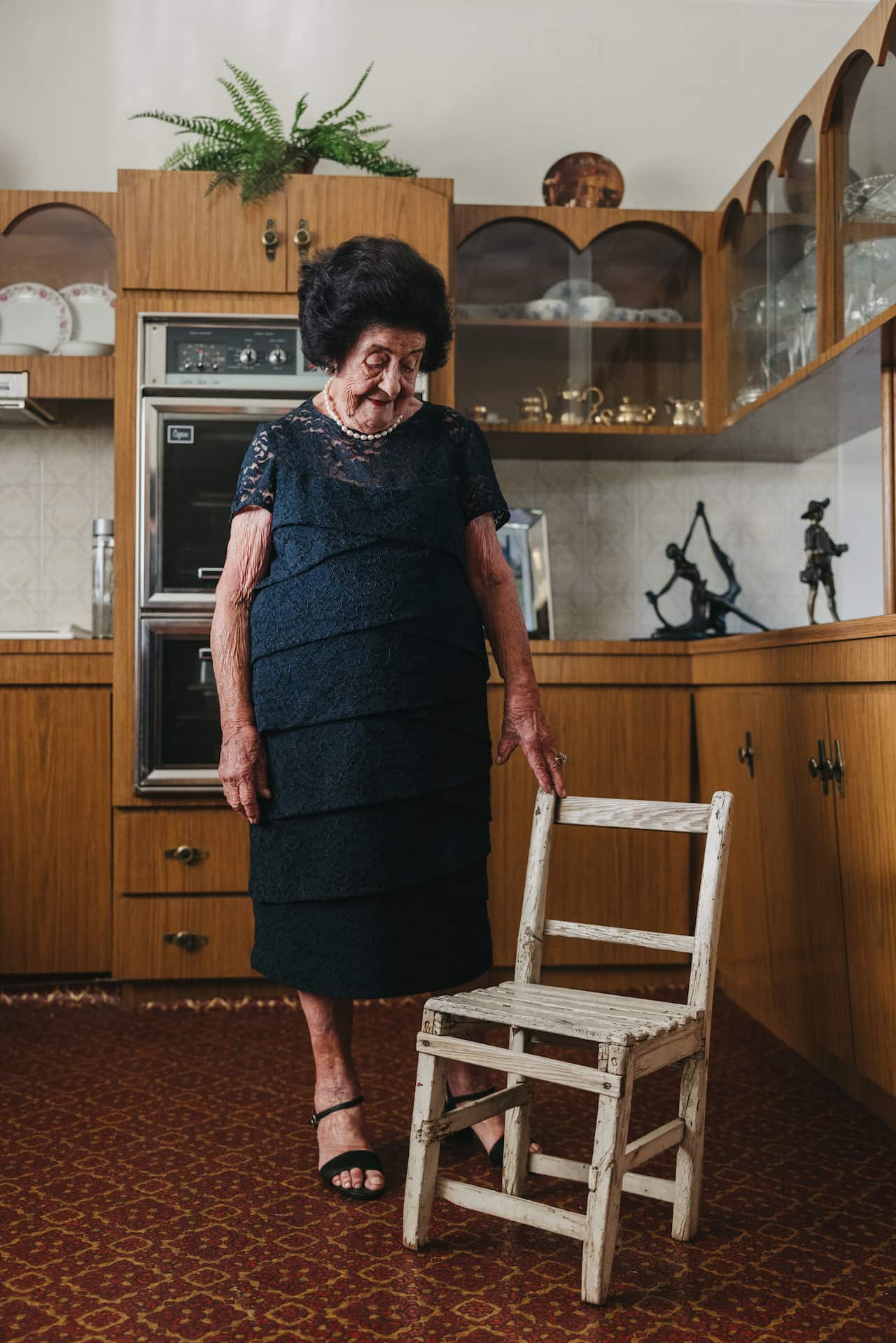 Nina Miragliotta stands in her kitchen proudly laying a hand on the chair her father made her 96 years ago