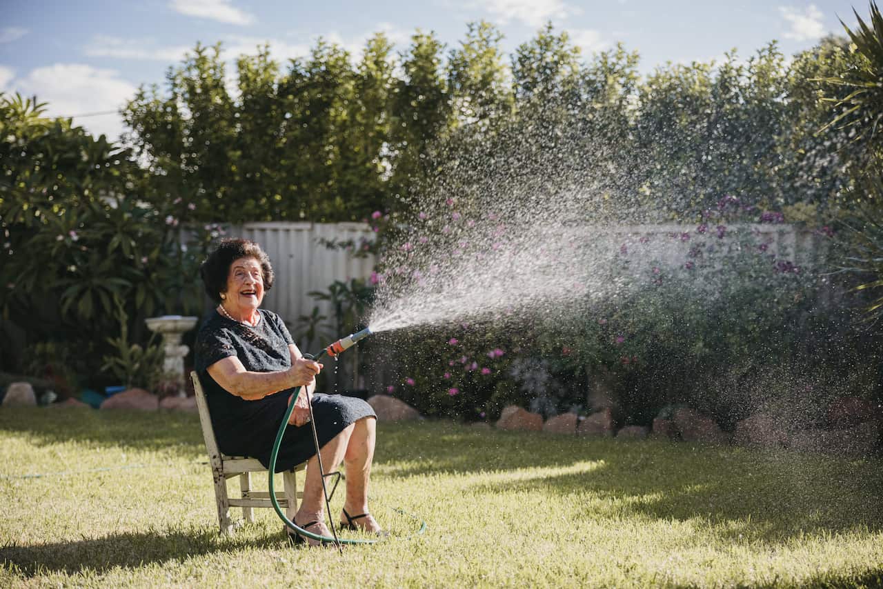 Nina uses her old wooden chair to sit on whilst she waters her garden