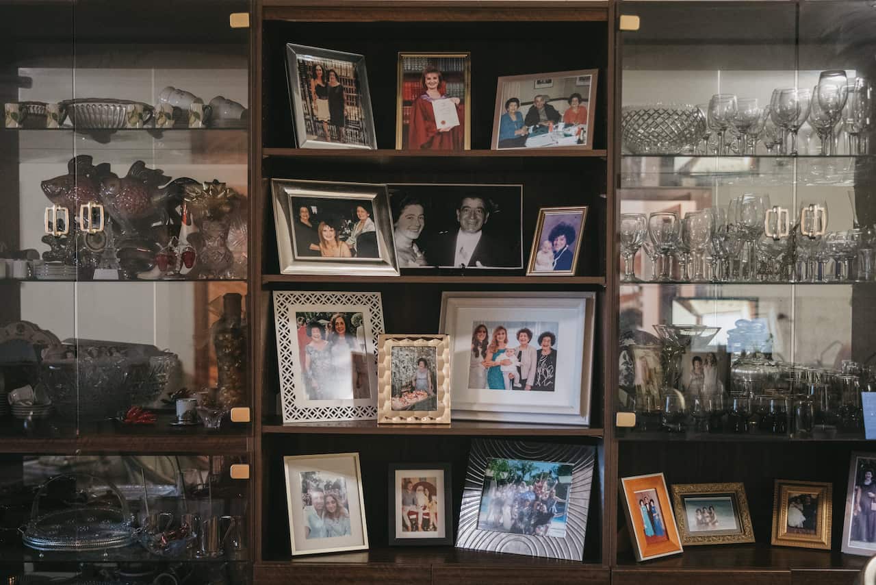 A cabinet of old photographs and glassware that holds memories of a big Italian family, suspended in time