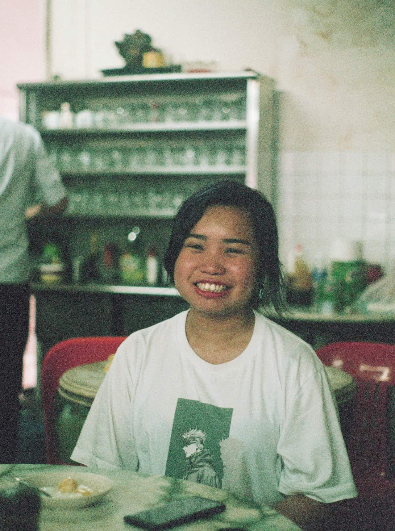 Young East Asian girl sitting in a restaurant, smiling.