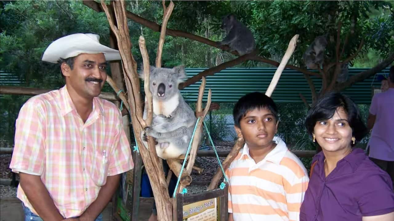 South Asian family at the zoo posing next to a koala.