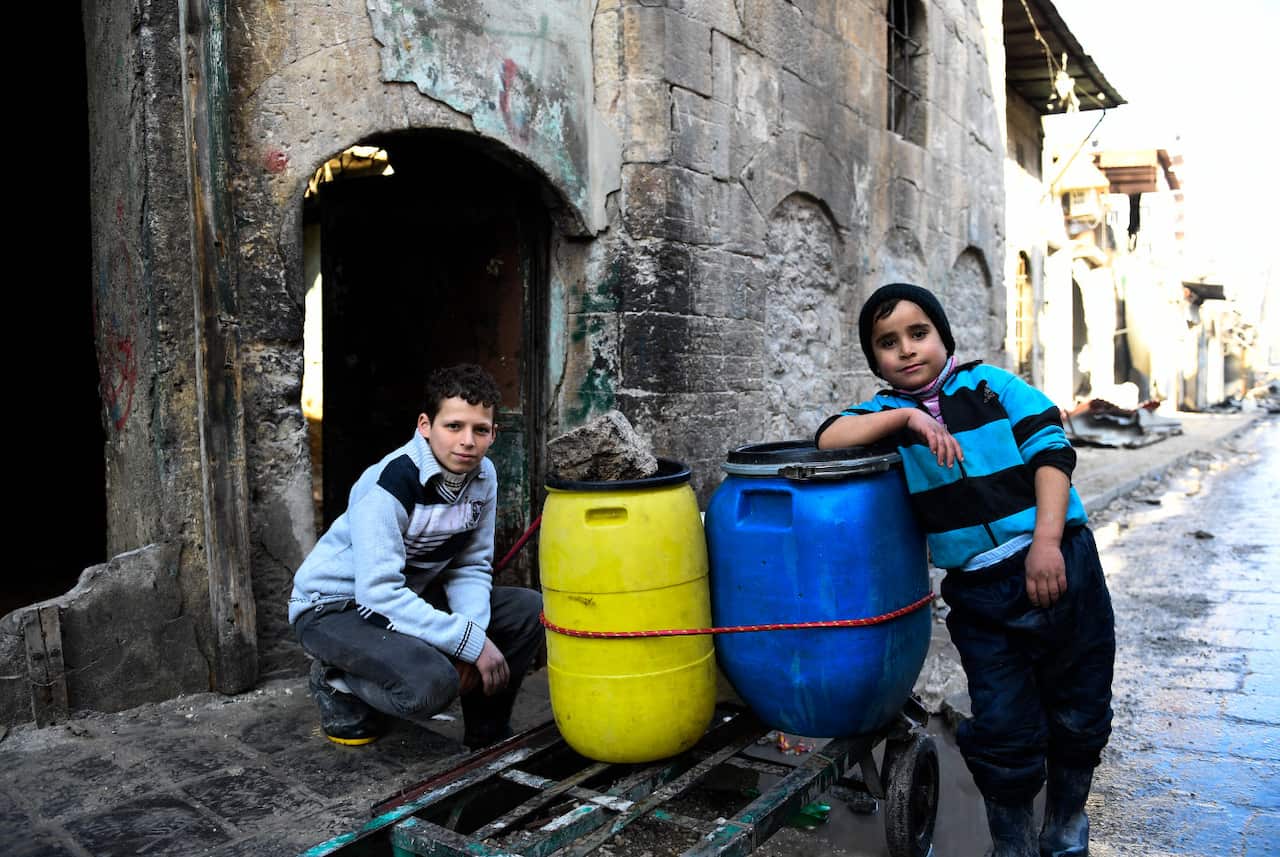 Two Syrian boys rest beside a cart they use to carry water back to their home in east Aleppo. 