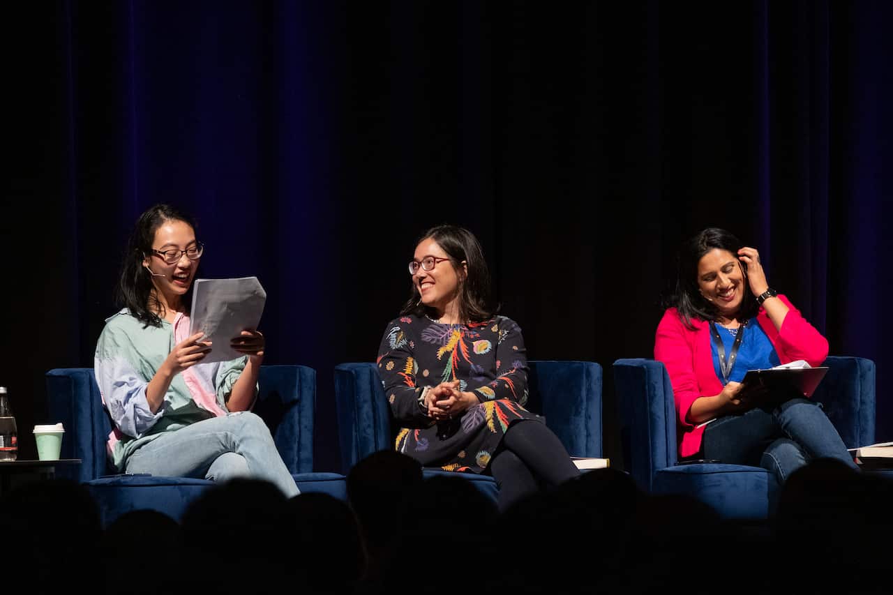 A young Asian woman reads on stage