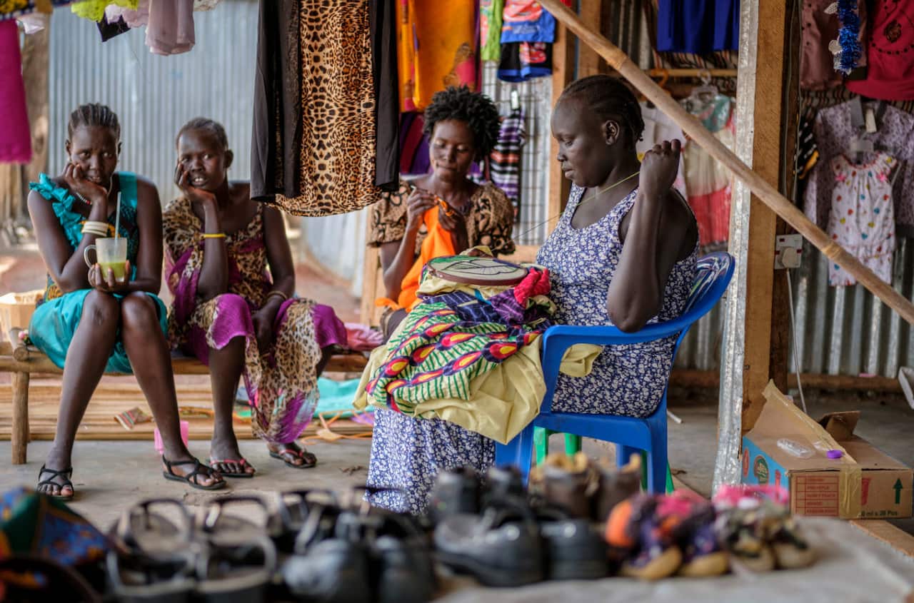 A South Sudanese woman mends a shirt for a customer at a market in Nymanzi refugee settlement in Northern Uganda.