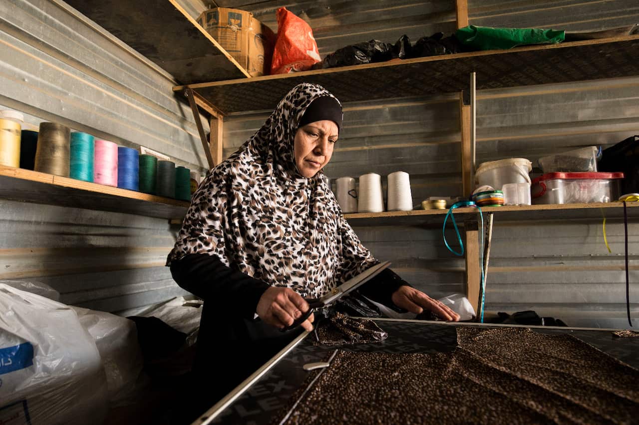 Um Riad works at a makeshift cutting table made from the floorboards of one of the UNHCR caravans.