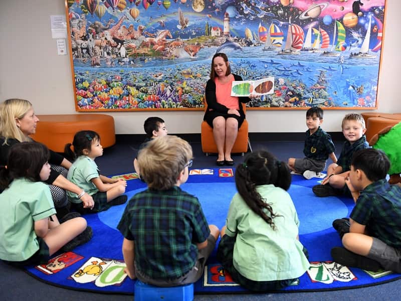 A teacher reads a story to young school students