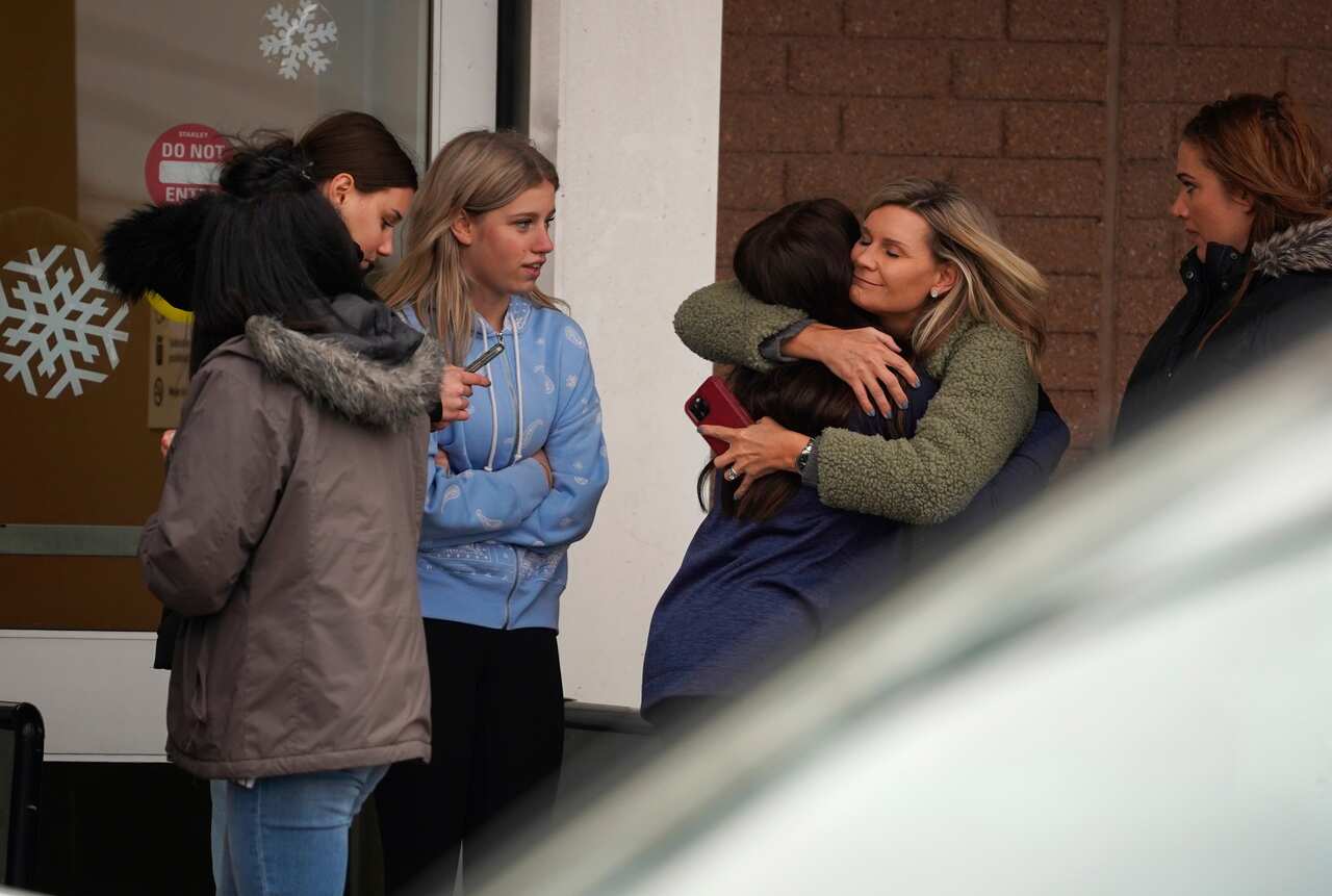 A parent hugs a child as others come to pick up students from the Meijer store in Oxford, Mich., following an active shooter situation at Oxford High School, Tuesday, Nov. 30, 2021.