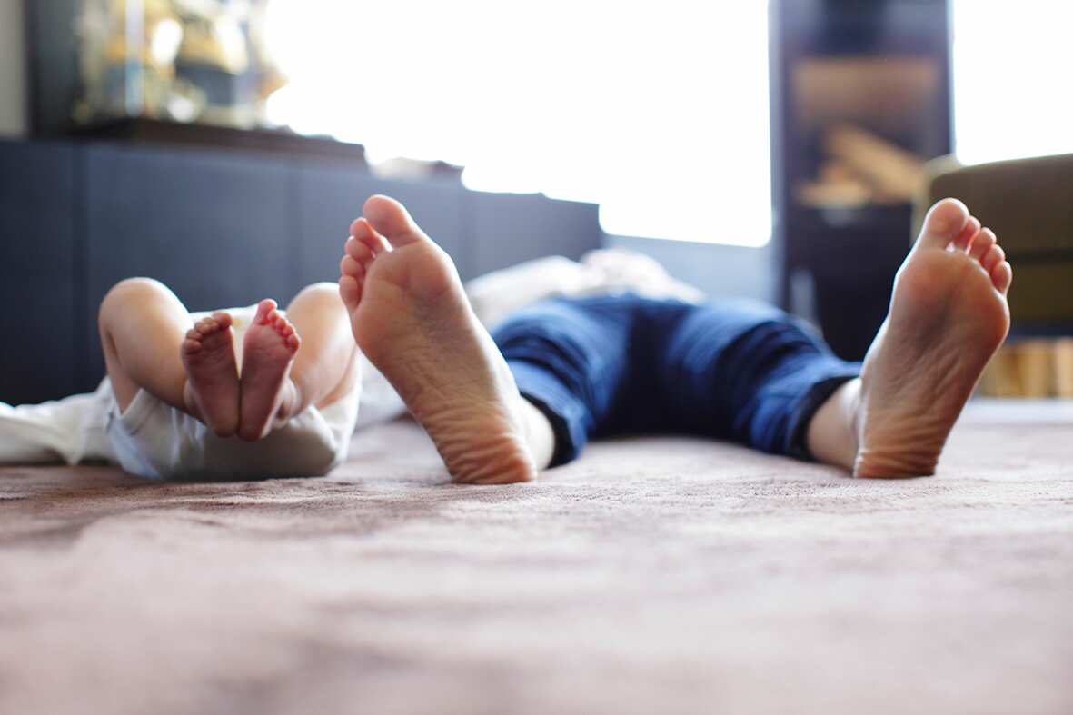 Foot of mother and baby lying on carpet