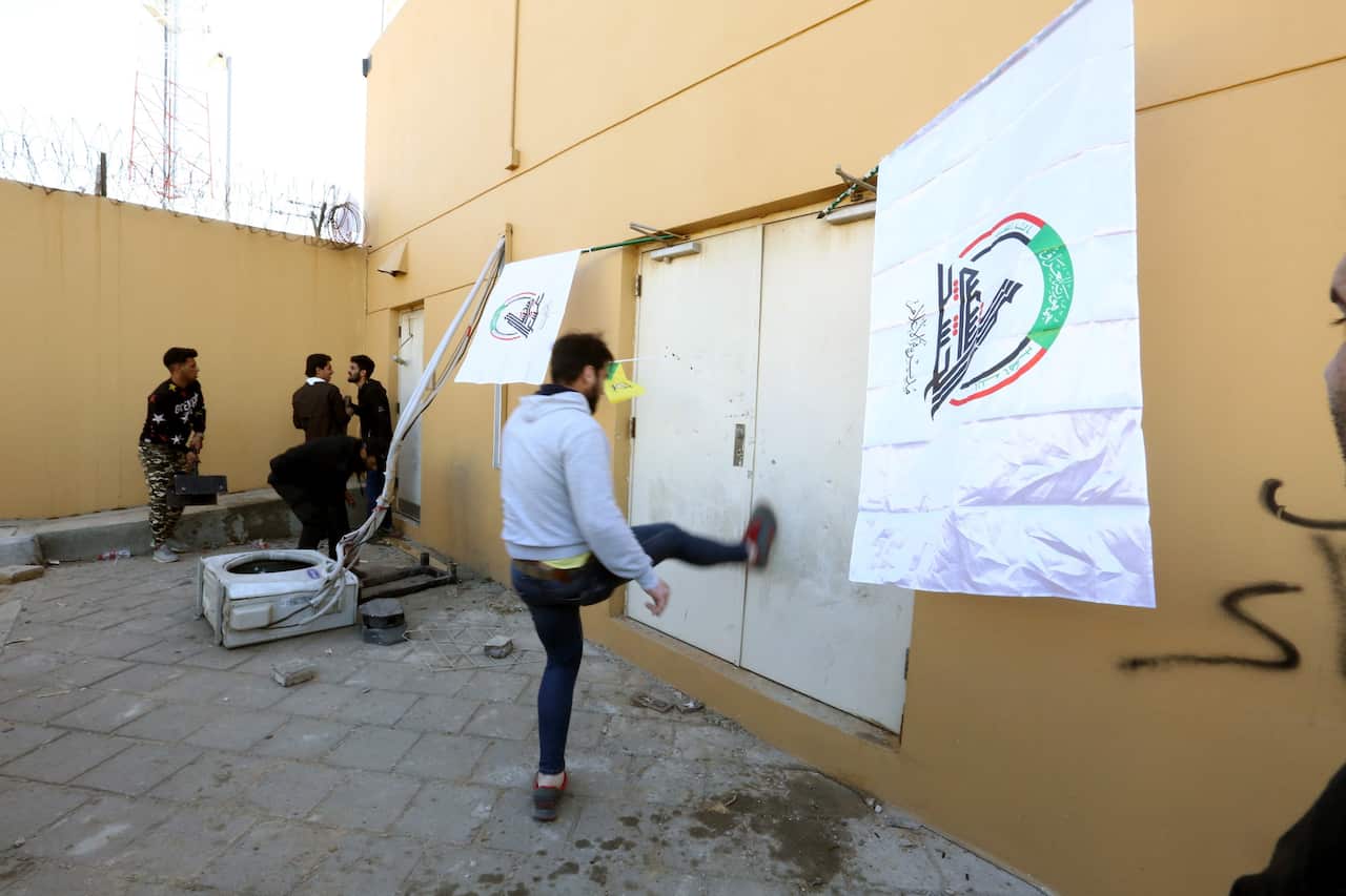 Members of Iraqi Shiite 'Popular Mobilization Forces' armed group and their supporters attack the entrance of the US Embassy during a protest in Baghdad, Iraq.