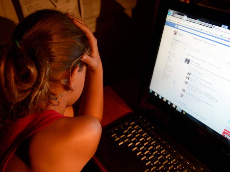 An upset young girl in front of a personal computer.