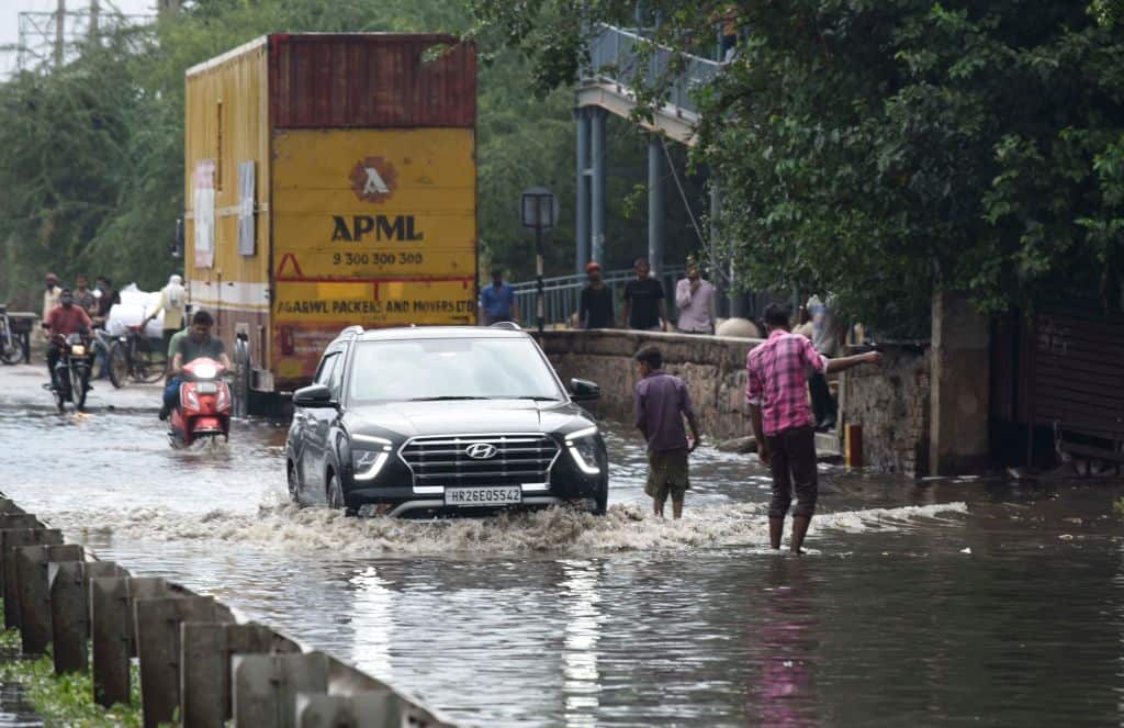 Commuters wade through a waterlogged stretch on the Delhi-Gurugram Expressway Service Road near Narsinghpur Village on 17 October, 2021 in Gurugram, India.