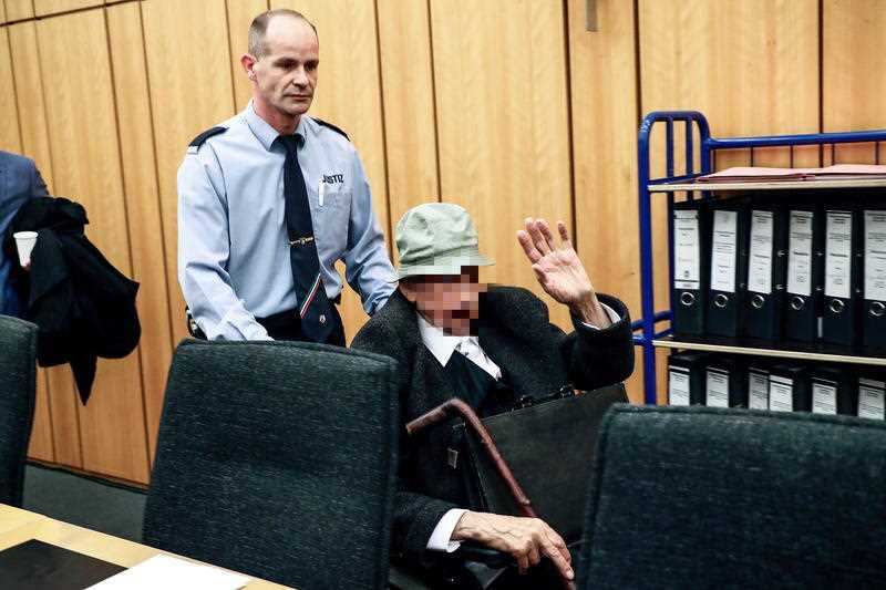 The accused Nazi guard is wheeled out of the court. He denies knowing anything about atrocities committed during the war.