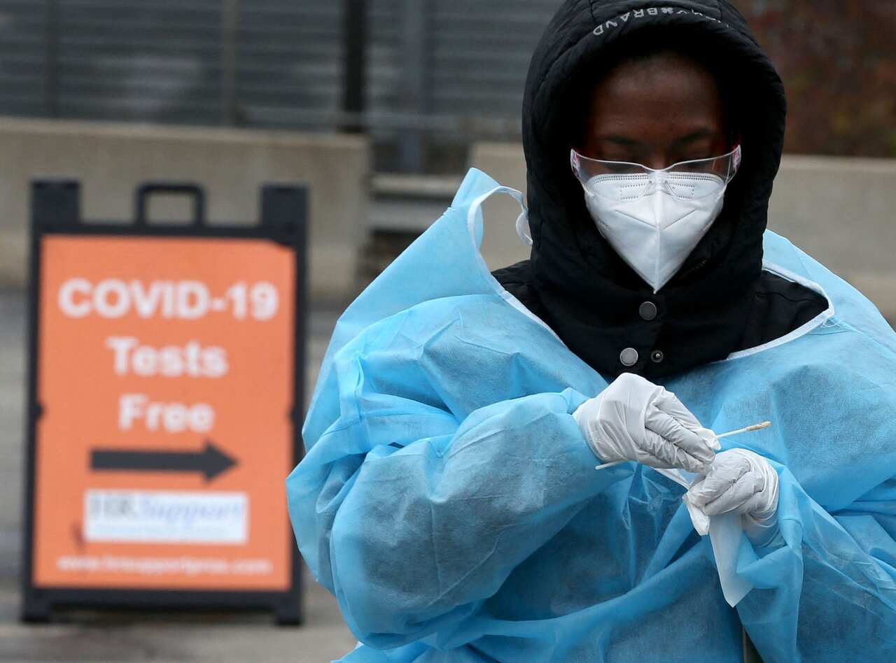 A health worker places a cotton swab into a tube after administering a COVID-19 test at the Foreman Mills Shopping Center in Chicago on Oct. 19, 2020