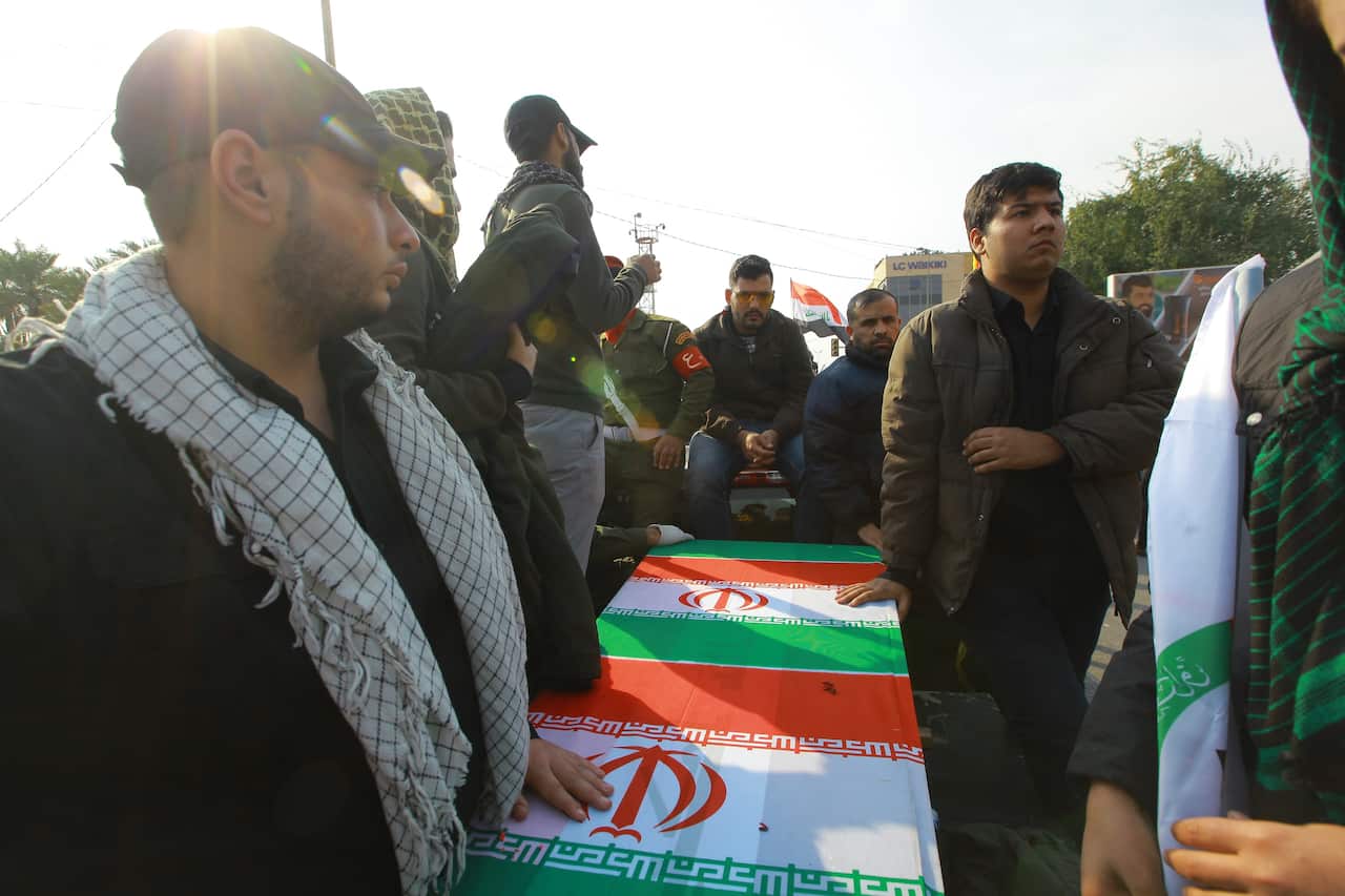 Mourners surround a car that carries a coffin during a funeral procession for Qassem Soleimani, the commander of Iran's elite Quds Force.